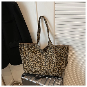 Detail of leopard print canvas tote bag on silver suitcase featuring long shoulder straps