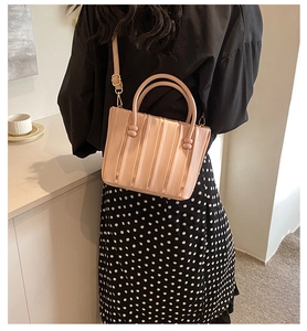 Detail showing the vertical pleats and golden metal hardware of the pink crossbody bag