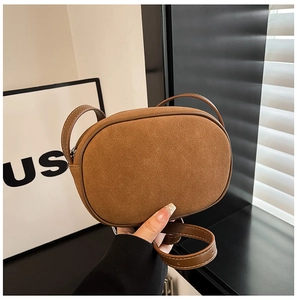 Detail of brown suede crossbody bag showing smooth leather trim and contrast stitching
