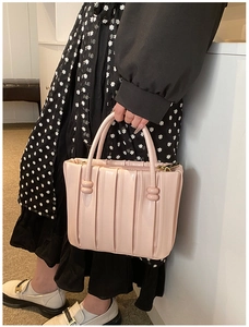 Close-up of pink pleated leather handbag featuring decorative bead buckle details