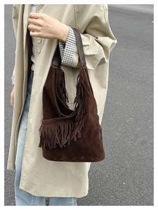 Dettaglio di una borsa a tracolla in pelle scamosciata marrone scuro con nappe boho fitte