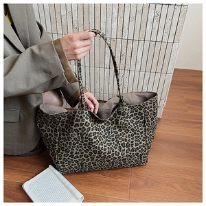 Detail of vintage leopard print canvas tote bag carried by a model in a gray suit