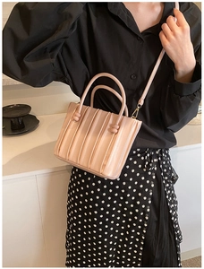 Detail of light pink pleated handbag with accordion texture and gold metal hooks