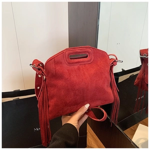 Detail of red suede handbag featuring decorative long tassels and an integrated top handle