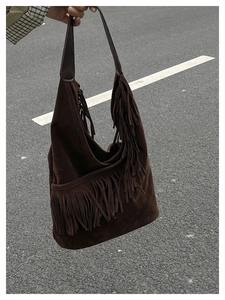 Dettaglio ravvicinato delle nappe in pelle scamosciata marrone su borsa a spalla vintage