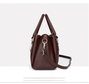 Dettaglio della borsa tote in pelle marrone scuro con eleganti anelli a D dorati e tracolla