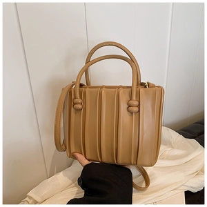 Detail of khaki pleated handbag with double handles and decorative spherical buckles