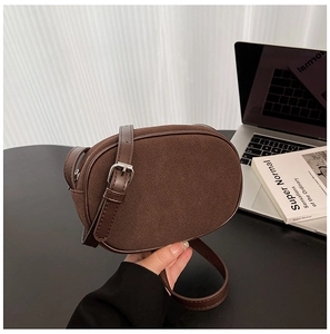 Close-up of caramel brown suede crossbody bag with adjustable leather strap and metal buckle