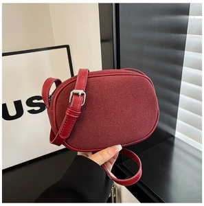 Detail of red suede mini bag showing matte texture and adjustable silver metal buckle strap