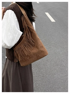 Dettaglio borsa a tracolla in pelle scamosciata marrone con frange e stile boho