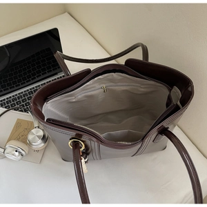 Interior view of chocolate tote bag with gray lining, zipper pocket, and beaded charm detail