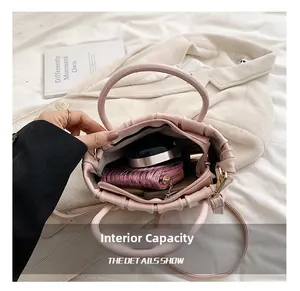 Internal capacity of pink pleated handbag showing cosmetics and wallet with top-down view