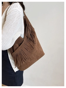 Dettaglio della borsa a spalla in camoscio marrone con lunghe frange boho e grande capienza