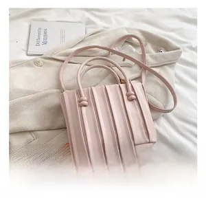 Detailed view of pink pleated handbag with dual round handles and adjustable strap