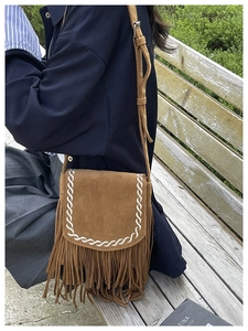 Dettaglio borsa in camoscio marrone con frange, cuciture intrecciate e stile boho