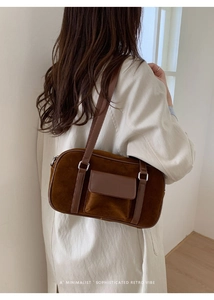 Detail view of a brown suede shoulder bag featuring a front pocket and retro minimalist style