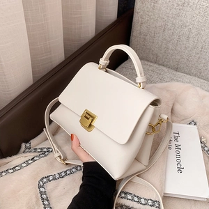 Classic white leather handbag with gold metal clasp and adjustable shoulder strap