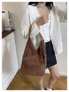 Dettaglio di una borsa hobo in camoscio marrone con lunghe nappe stile bohémien