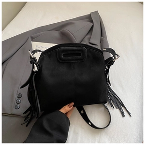 Detail of black suede bag featuring long fringe tassels and a comfortable cutout handle