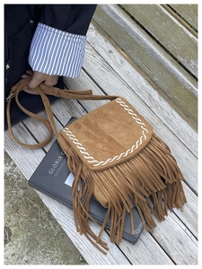 Dettaglio borsa a tracolla boho in camoscio marrone con frange e cuciture bianche