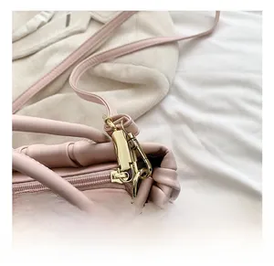 Detail of pink pleated bag with gold-tone hardware, smooth zipper, and lobster clasp