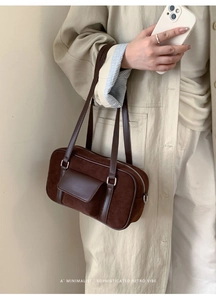 Detail of dark brown suede baguette bag with leather strap and silver hardware accents