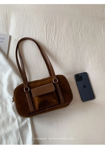 Detail of a brown suede hobo bag featuring a leather flap pocket and thin shoulder straps