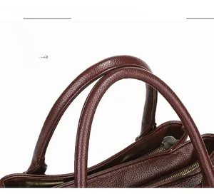 Dettaglio borsa in pelle marrone scuro con grana litchi, doppi manici e cerniera in metallo