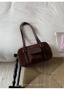 Detail of dark brown suede shoulder bag with retro metal buckle and leather pocket