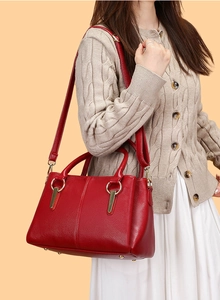 Dettaglio della borsa tote in pelle rossa martellata con anelli dorati e tracolla regolabile