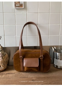 Detailed close-up of dark brown suede shoulder bag with a magnetic leather pocket