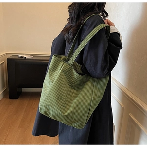 Detail of green checkered canvas tote bag showing textured fabric and wide shoulder straps