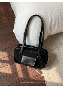 Detail of minimalist black suede shoulder bag with front flap pocket and texture contrast