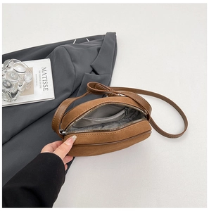 Close-up of brown suede crossbody bag showing interior lining and zipper pocket
