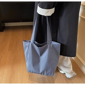 Detailed macro view of the blue and white checkered canvas tote bag with long handles