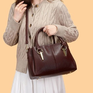 Dettaglio borsa tote in pelle bordeaux con finiture dorate su outfit casual