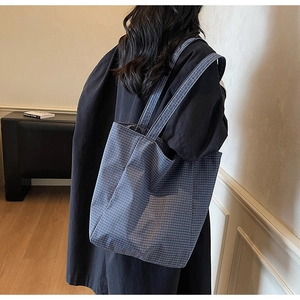 Detail of blue and white checkered canvas tote bag shown on model for size and fit