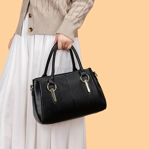 Dettaglio di borsa tote in pelle martellata nera con eleganti anelli dorati e metallo