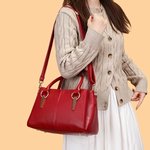 Dettaglio della borsa tote in pelle martellata rossa con hardware dorato e piedini in metallo