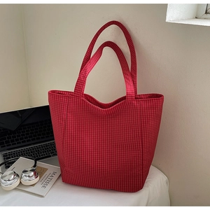 Detail of red checkered canvas tote bag with laptop and headphones on office desk
