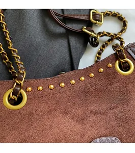 Detail of dark brown suede bag featuring gold dome studs and woven chain strap