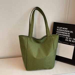 Green checkerboard canvas tote bag with minimalist shoulder straps on a white surface