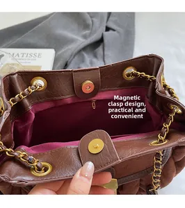 Detail shot of brown bucket bag featuring magnetic snap closure and golden chain strap