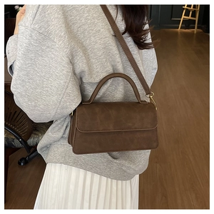 Gros plan d'un sac à main vintage marron avec bandoulière et détails dorés élégants