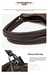 Detail of dark brown leather tote handle with polished metallic ring and stitching