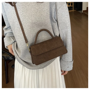 Mannequin portant un petit sac carré marron foncé mat avec garniture dorée chic