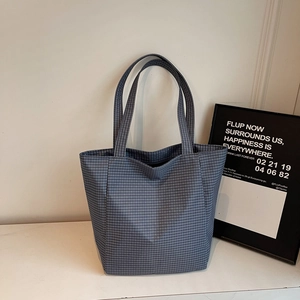 Detail view of large checkered canvas tote bag in dark blue-grey on a minimalist desk