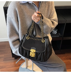Detail of black pleated shoulder bag featuring vintage gold lock and double chain strap