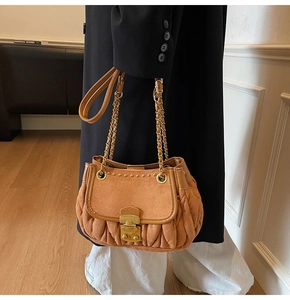 Detail of camel suede shoulder bag with pleated sides and gold rivet accents