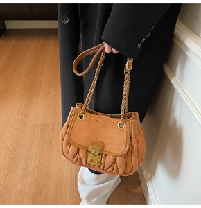 Detail of caramel pleated suede bag featuring vintage gold lock and chain strap